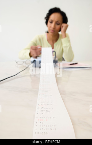 Femme lisant Adding Machine Tape Banque D'Images