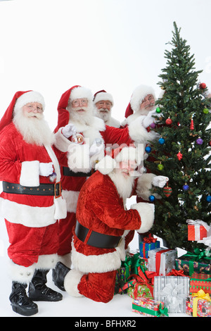 Groupe d'hommes habillés en Père Noël decorating Christmas Tree Banque D'Images