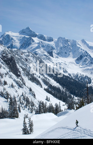 Un raquetteur solitaire sur une journée de printemps ensoleillée à Mount Baker avec le Mont Shuksan dans distance Snoqualmie National Forest Washington USA Banque D'Images