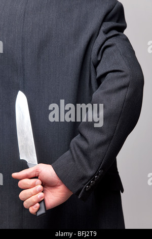 Close up of a businessman avec un couteau derrière son dos. Banque D'Images