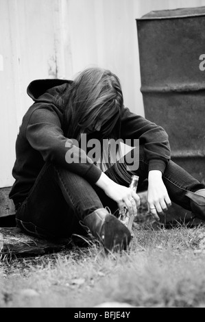 Jeune fille ivre un alcopop potable, affalé dans une rue. Banque D'Images
