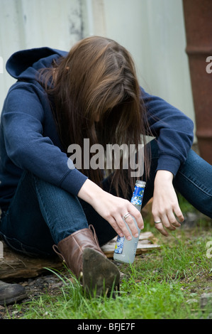 Jeune fille ivre un alcopop potable, affalé dans une rue. Banque D'Images