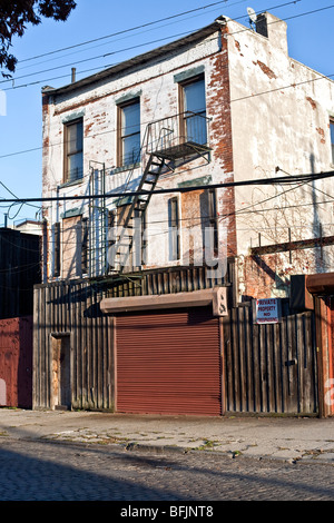 Grungy attrayant bâtiment résidentiel en briques peintes en blanc avec des modifications commerciales maladroite sur rez-de-chaussée Red Hook Brooklyn Banque D'Images