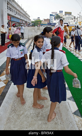 Ecolières leur lavant les pieds avant d'entrer dans le Temple d'or. Amritsar. Punjab. L'Inde Banque D'Images