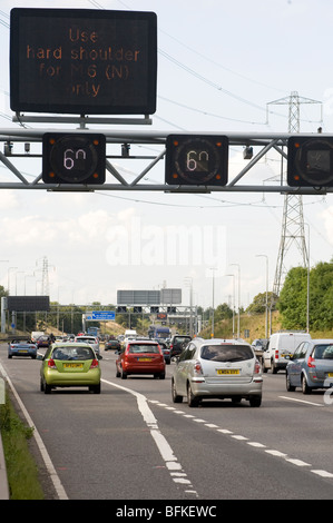 Limite de vitesse variable de la section M42 montrant le trafic à l'aide de la bande d'arrêt d'urgence à tenter de réduire la congestion aux heures de pointe. Banque D'Images