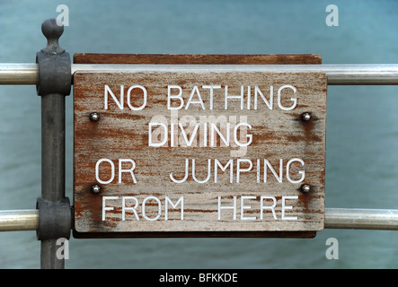 Un panneau en bois, avise la population de ne pas plonger ou sauter dans la mer depuis la jetée. Banque D'Images