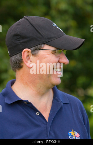 Âge moyen à l'extérieur de l'homme blanc à la recherche de l'appareil photo et souriant tout en portant une casquette et des lunettes Banque D'Images