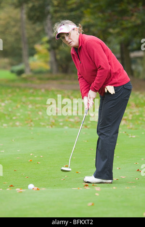 Un blanc d'âge moyen golfeuse mise sur le green Banque D'Images