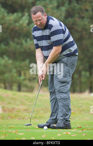 A middle aged white male golfer mise sur le green Banque D'Images