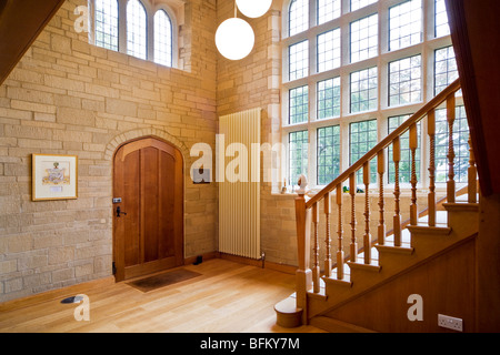 Escalier en bois porte d'entrée et couloir de pierre et de fenêtres à meneaux dans une grande maison contemporaine moderne English UK Banque D'Images