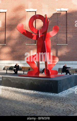 Sculpture métal rouge vif lunatique figure en équilibre sur un chien par Keith Haring installés dans de petites Plaza Manhattan Banque D'Images