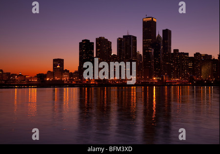 La ville de Chicago compte dans le lac Michigan au crépuscule après le coucher du soleil avec un ciel rose pourpre du Navy Pier Banque D'Images