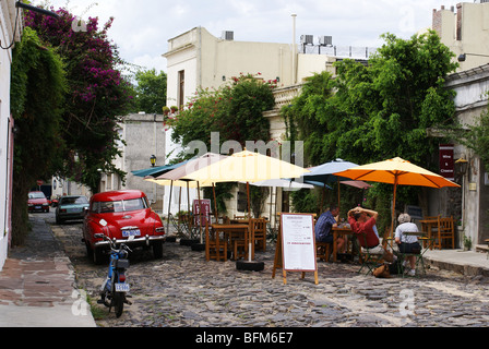 Les touristes en terrasse de café dans la vieille rue pavée de Colonia del Sacramento, Uruguay. Banque D'Images