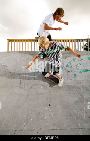 3 garçons faisant des tours dans le skate park avec soleil couchant, Nouvelle-Zélande, Banque D'Images