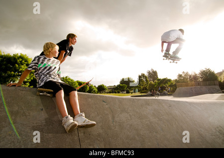 3 garçons faisant des tours dans le skate park avec soleil couchant, Nouvelle-Zélande, Banque D'Images