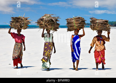 Kenya Mombasa. Les femmes portent sur leur tête de noix de coco séchées makuti (feuilles de palmier utilisé comme matériau de couverture) sur la côte sud du Kenya. Banque D'Images
