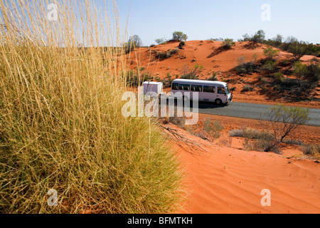 L'Australie, Territoire du Nord, Lasseter Highway. Un bus conduit par le paysage de désert aride du centre de l'Australie. Banque D'Images