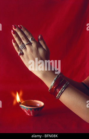 BDR 60856 : Diwali festival deepawali ; femme indienne dans Namaskar et deepak lampe à pétrole sur fond rouge Banque D'Images