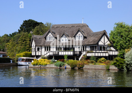 Une maison au toit de chaume par la rivière Bure dans Horning, Norfolk Broads, England, UK. Banque D'Images