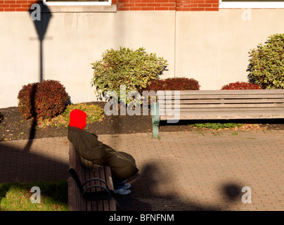 Man in red hood sur banc de parc. Banque D'Images