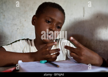 Les enfants ont classe de renfort à la maison. Garçon noir en comptant avec l'aide des doigts. Le Brésil. Banque D'Images