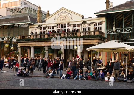 Des foules de gens et de touristes devant le Punch et Judy pub Covent Garden en regardant la performance d'un artiste de rue. Banque D'Images