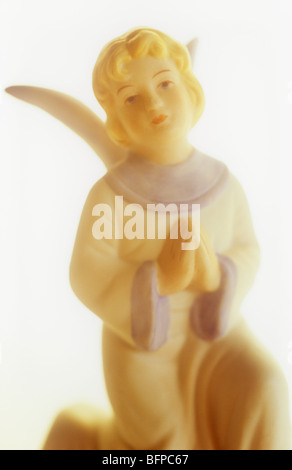 Close up impressionniste dans la chaude lumière de l'ange d'un enfant en robe blanche et bleue avec les mains jointes en prière et les yeux au ciel Banque D'Images