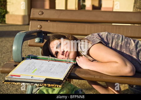 Caucasian teenage girl 13-14 ans ans détend dans sun tout en faisant ses devoirs sur un banc à l'extérieur. M. Californie © Myrleen Pearson Banque D'Images