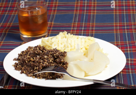 Haggis, navets, purée de pommes de terre et un verre de whisky sur un fond tartan - les ingrédients d'une soirée Burns supper Banque D'Images