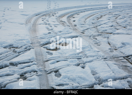 Pneu de voiture imprime dans la neige au sol couvert de parking Banque D'Images