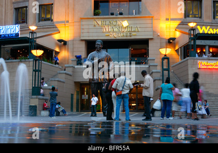 Les touristes se faisant passer à côté d'une statue de Nelson Mandela à la place Mandela à Sandton Banque D'Images