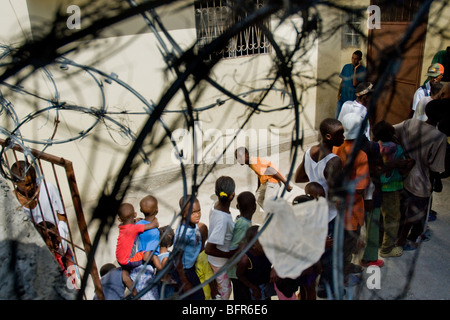 Une file d'enfants en attente dans le centre de distribution alimentaire de la paroisse Sainte Claire à Port-au-Prince, Haïti. Banque D'Images