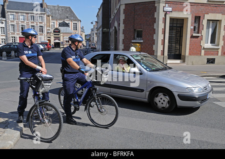 Deux polices municipales municipale sur les bicyclettes s'arrêter pour aider un automobiliste en argent Citroen car trouver son chemin à Amiens France Banque D'Images