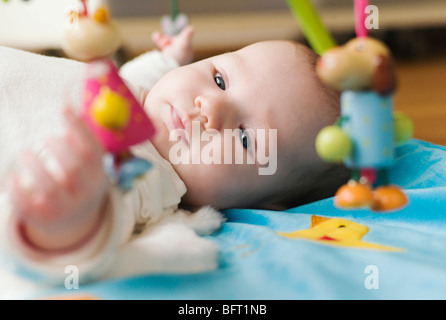 Baby Lying on Blanket avec jouets Banque D'Images