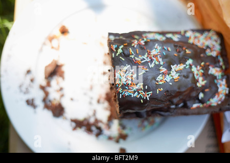 La moitié du gâteau au chocolat avec la plaque sur Sprinkles Banque D'Images