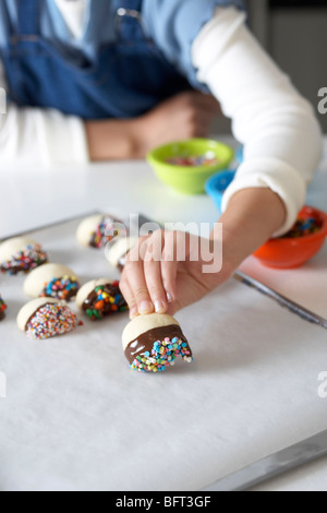 Woman Making Sablés glacés au chocolat avec Sprinkles Banque D'Images