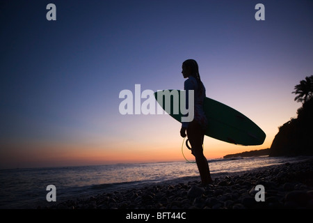 Surfeur sur la plage en admirant le coucher du soleil, Punta Burros, Nayarit, Mexique Banque D'Images