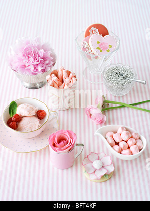 Verres et vaisselle pleine de bonbons et de fleurs Banque D'Images