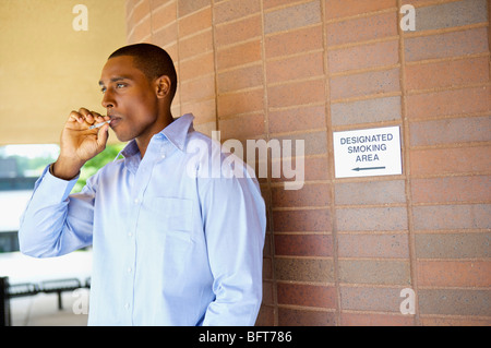 Man Smoking a cigarette dans les zones désignées Banque D'Images