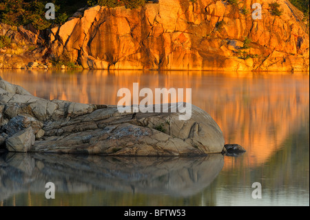 Falaises de granit reflété dans le lac George à l'aube, le Parc provincial Killarney, Ontario, Canada Banque D'Images