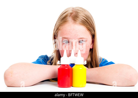 Fille de s'asseoir avec les bras croisés avec des pots de peinture à base d'eau à l'avant Banque D'Images