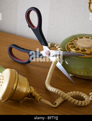 Une paire de ciseaux couper un cordon téléphonique. Banque D'Images