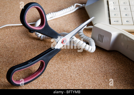 Une paire de ciseaux couper un cordon téléphonique. Banque D'Images