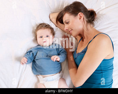 Couché à côté de mère baby on bed Banque D'Images