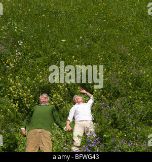 Senior couple lying in field of flowers Banque D'Images