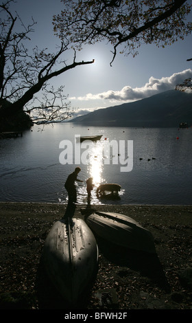 Salon du Loch Lomond, Ecosse. La silhouette d'une mère, la fille et le chien la pagaie dans l'eau à Rowardennan shores. Banque D'Images