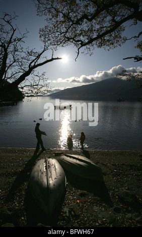 Salon du Loch Lomond, Ecosse. La silhouette d'une mère, la fille et le chien la pagaie dans l'eau à Rowardennan shores. Banque D'Images