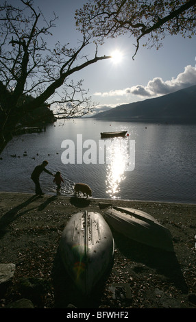 Salon du Loch Lomond, Ecosse. La silhouette d'une mère, la fille et le chien la pagaie dans l'eau à Rowardennan shores. Banque D'Images