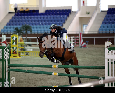 Une femme koweïtienne showjumper en action lors d'un concours régional tenu au Qatar Equestrian Federation's indoor arena à Doha Banque D'Images