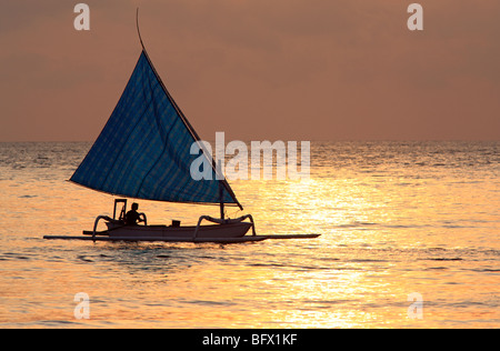 Jukung, ou bateau de pêche traditionnel balinais avec pêcheur et voile, tôt le matin, Tulamben, Bali, Indonésie Banque D'Images